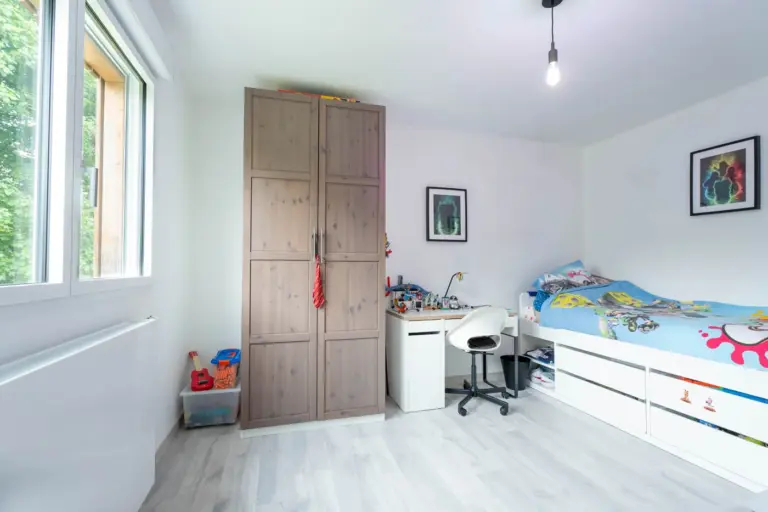 Chambre d'enfant aménagée dans la surélévation bois : bureau, lit et rangements