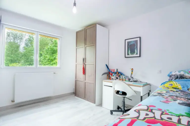 Chambre d'enfant de la surélévation en ossature bois, fenêtre ouverte sur le jardin