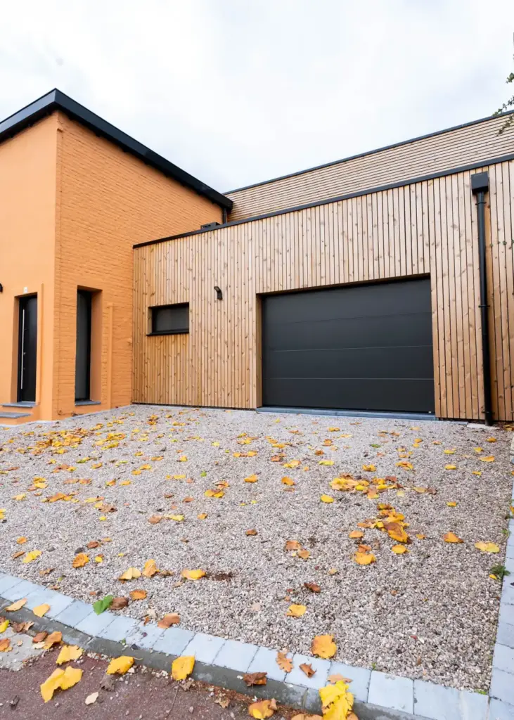 Garage bois accolé à la maison, vu depuis l'allée en gravier
