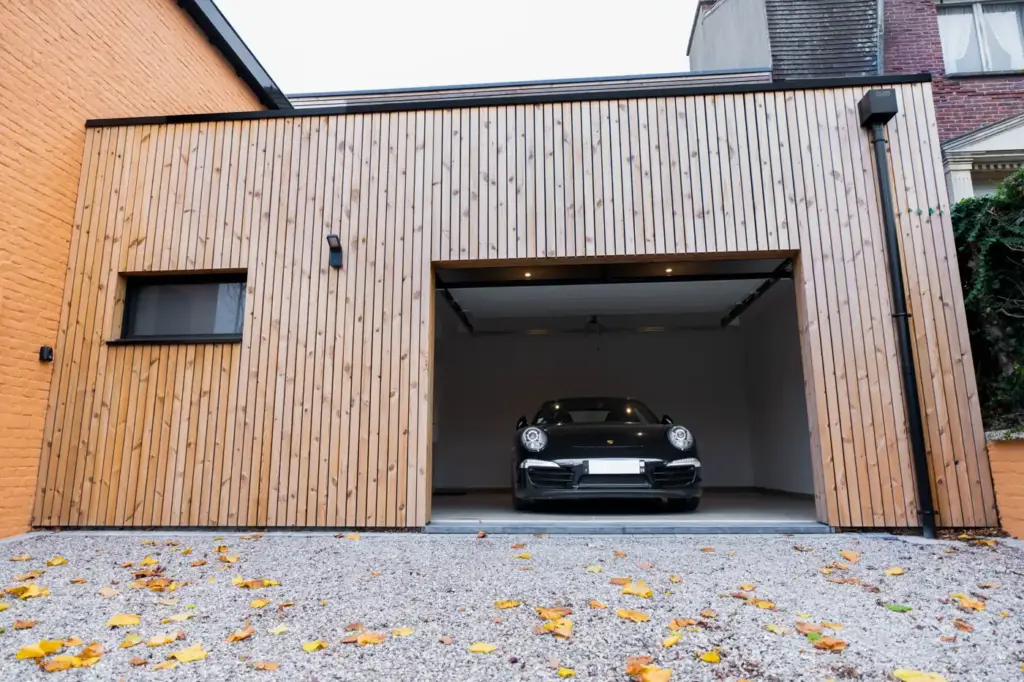 Garage bois porte ouverte, voiture rangée à l'intérieur sous éclairage encastré