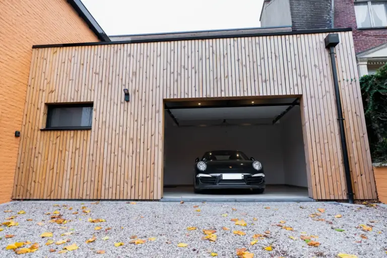 Extension de maison : tous les types pour agrandir sans déménager 14 Garage bois porte ouverte, voiture rangée à l'intérieur sous éclairage encastré