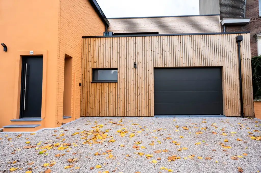 Façade d'un garage bois en kit avec porte sectionnelle anthracite et fenêtre en bandeau
