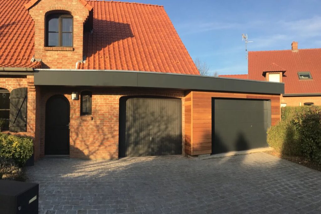 Garage bois à toit plat accolé à une maison de brique rouge, deux portes sectionnelles anthracite