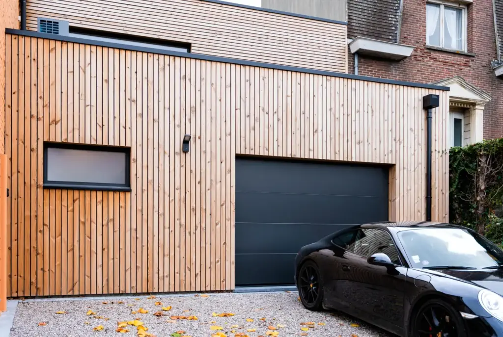 Voiture garée devant un garage en ossature bois au bardage vertical