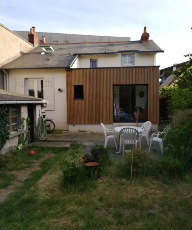 Extension en bois à bardage vertical accolée à une maison ancienne, vue depuis le jardin