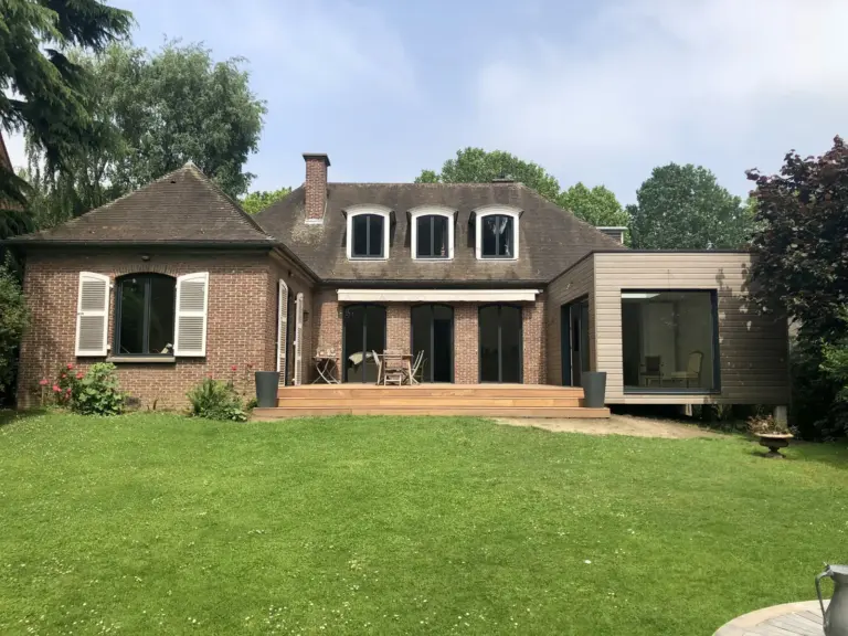 Extension en bois vitrée accolée à une maison en brique avec terrasse