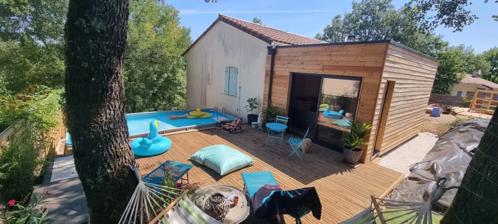 Extension en bois avec grande baie vitrée donnant sur une terrasse en bois et une piscine