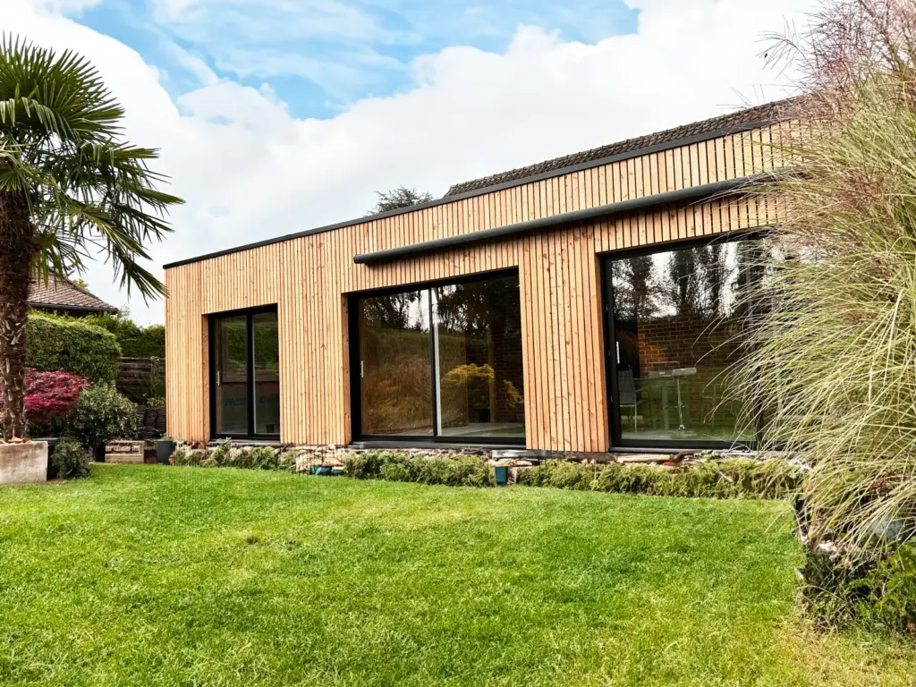 Extension en bois à toit plat avec grandes baies vitrées donnant sur le jardin